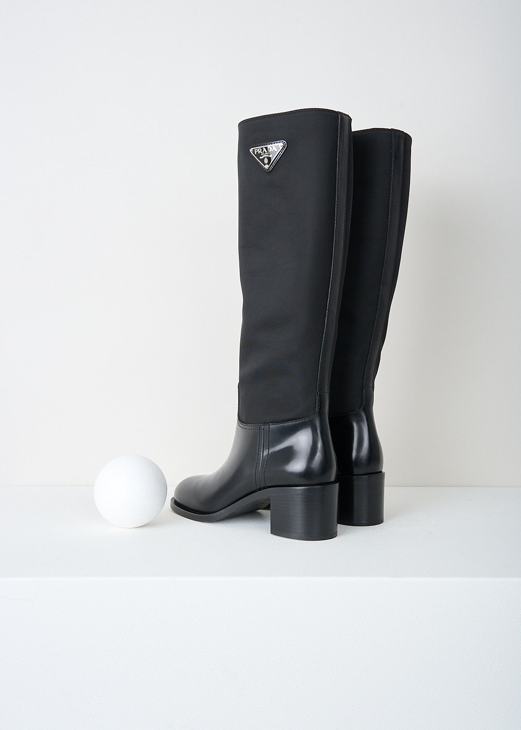 Prada, High black Re-Nylon boots, 3LFU_SPAZZOLATO_NYLON_1W411M_F0002_NERO, Black, Back, These high slip-on boots have a Re-Nylon shaft and a high-shine leather vamp and heel. On the shaft, the brand's signature triangle logo can be found. These boots have rubber platform soles with a small heel.

