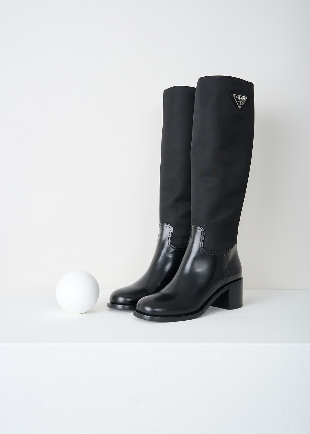 Prada, High black Re-Nylon boots, 3LFU_SPAZZOLATO_NYLON_1W411M_F0002_NERO, Black, Front, These high slip-on boots have a Re-Nylon shaft and a high-shine leather vamp and heel. On the shaft, the brand's signature triangle logo can be found. These boots have rubber platform soles with a small heel.

