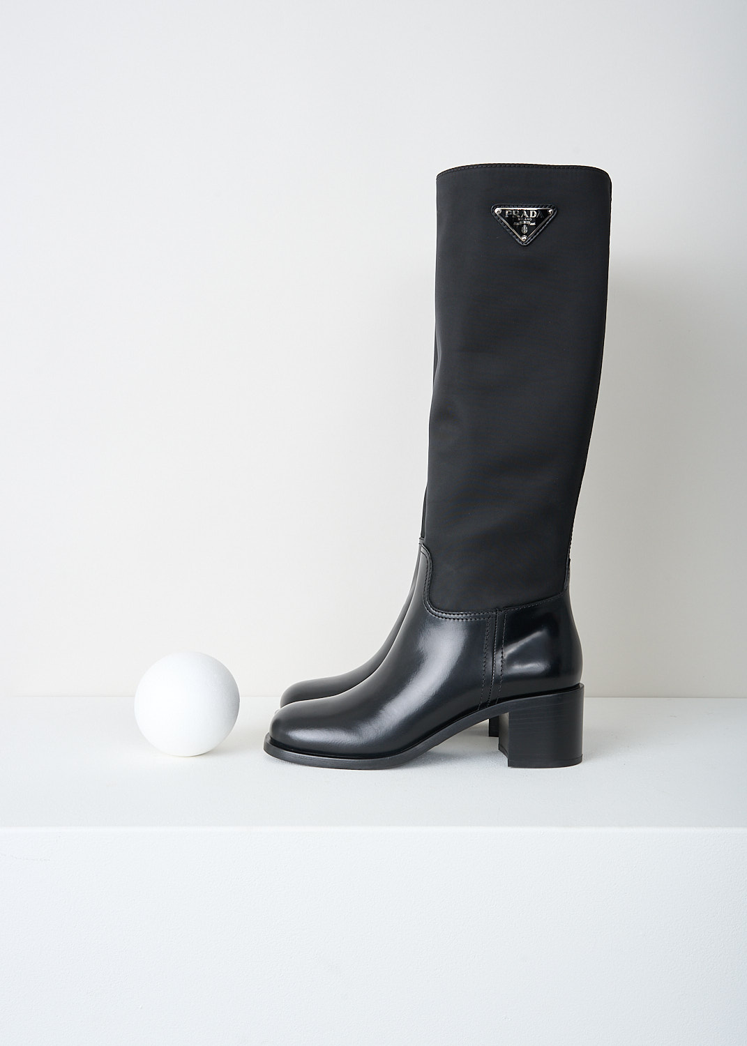 Prada, High black Re-Nylon boots, 3LFU_SPAZZOLATO_NYLON_1W411M_F0002_NERO, Black, Side, These high slip-on boots have a Re-Nylon shaft and a high-shine leather vamp and heel. On the shaft, the brand's signature triangle logo can be found. These boots have rubber platform soles with a small heel.

