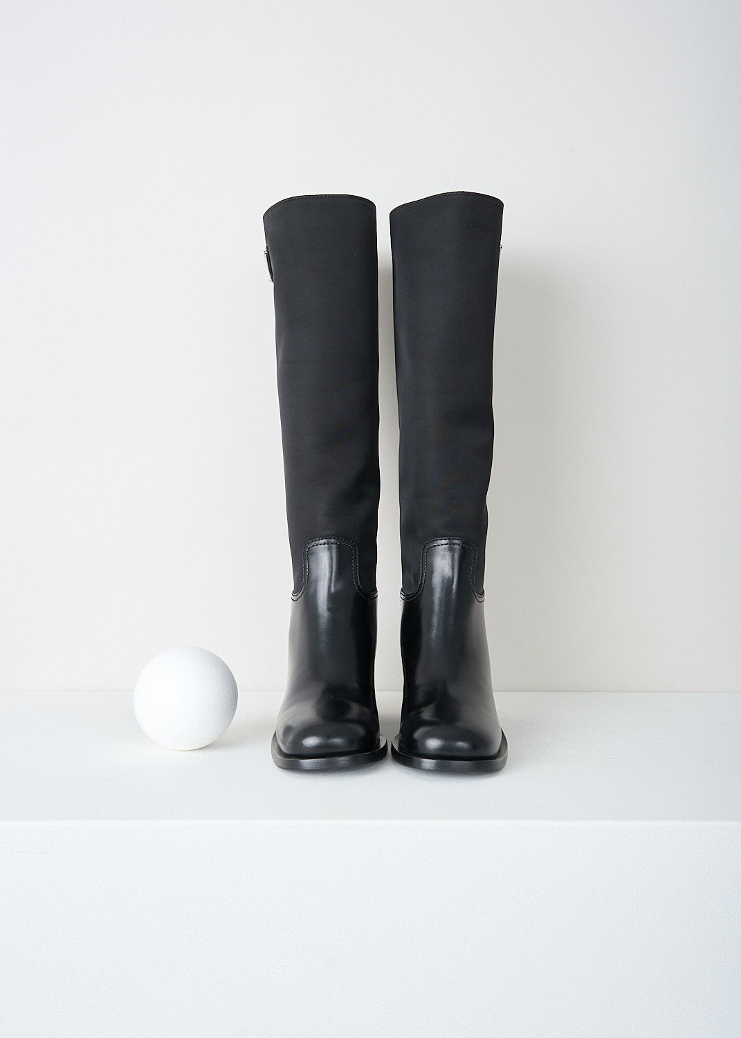 Prada, High black Re-Nylon boots, 3LFU_SPAZZOLATO_NYLON_1W411M_F0002_NERO, Black, Top, These high slip-on boots have a Re-Nylon shaft and a high-shine leather vamp and heel. On the shaft, the brand's signature triangle logo can be found. These boots have rubber platform soles with a small heel.

