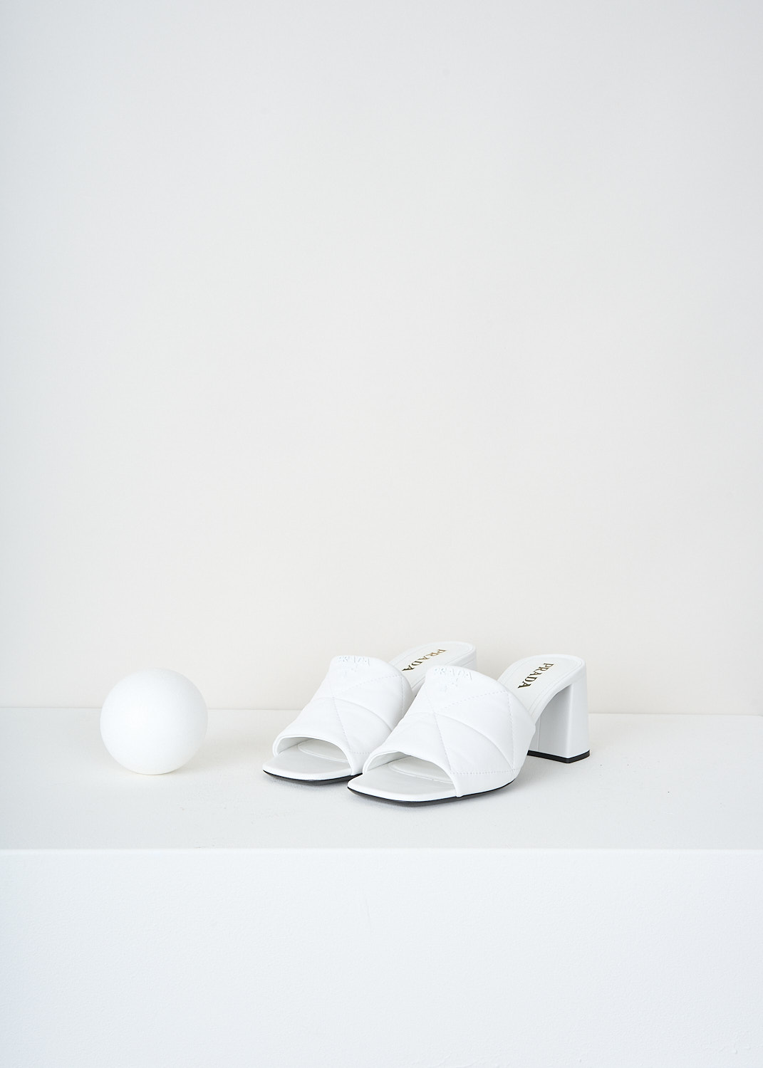 Prada, White matelassé mules, 038_NAPPA_1XX583_F0009_BIANCO, White, Front, These white open-toe mules have a broad matelassé strap across the vamp. These mules have a blocked heel.

