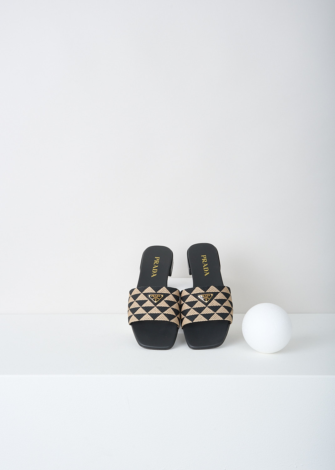 Prada, Black-and-beige triangolo slides, 3LK6_TRIANGOLO_JACQUARD_1XX637_F0Y30_NERO_CORDA_010, Black, Beige, Print, Top, These slip-on slides have a broad strap with a black-and-beige triangolo jacquard print. On the strap, the brand's triangle logo can be found in gold-tone metal. These slides have a small heel.
