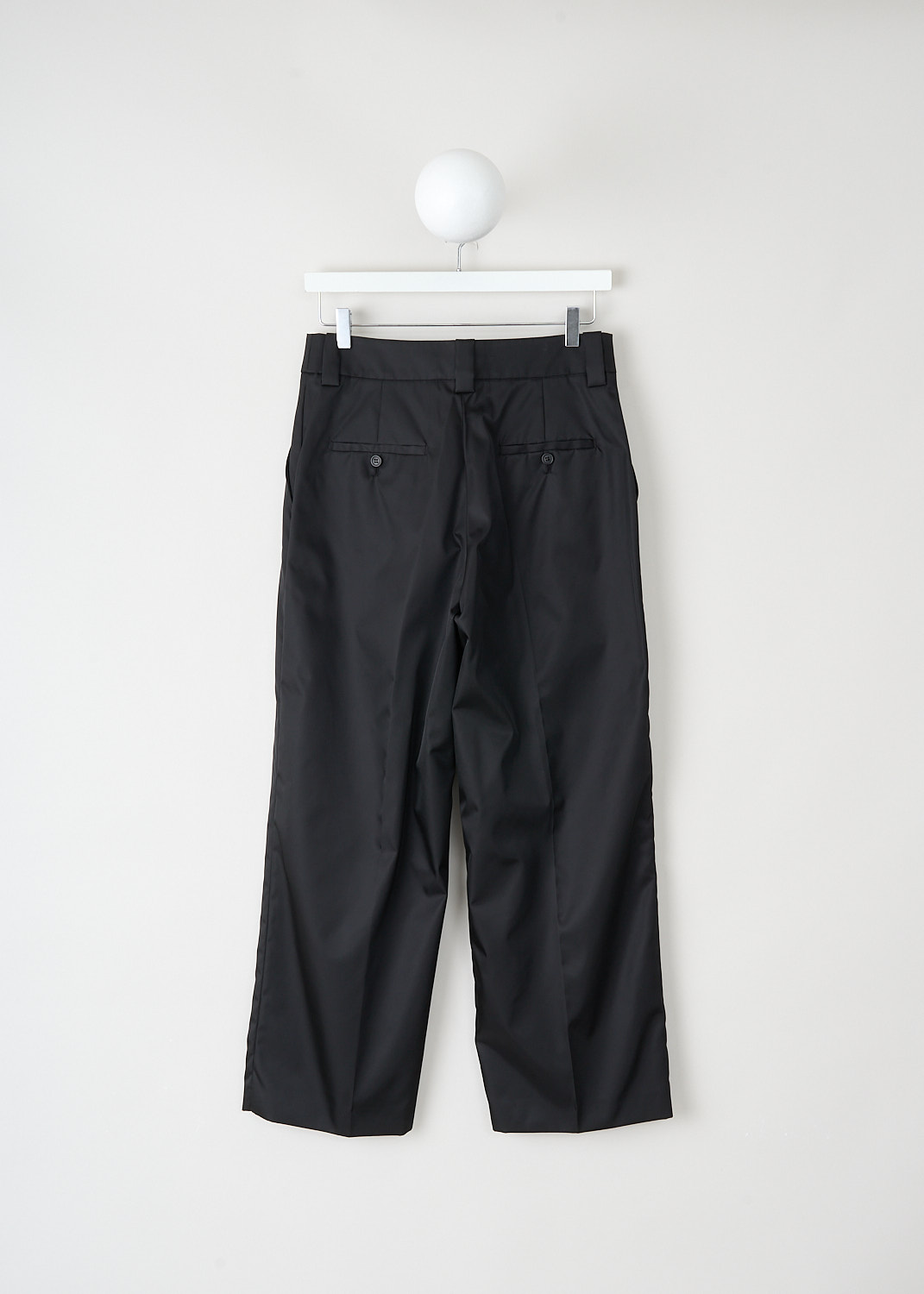 Back view of black Prada trousers with buttoned welt pockets and wide-leg silhouette at Kiki's Stocksale luxury designer outlet Maastricht.