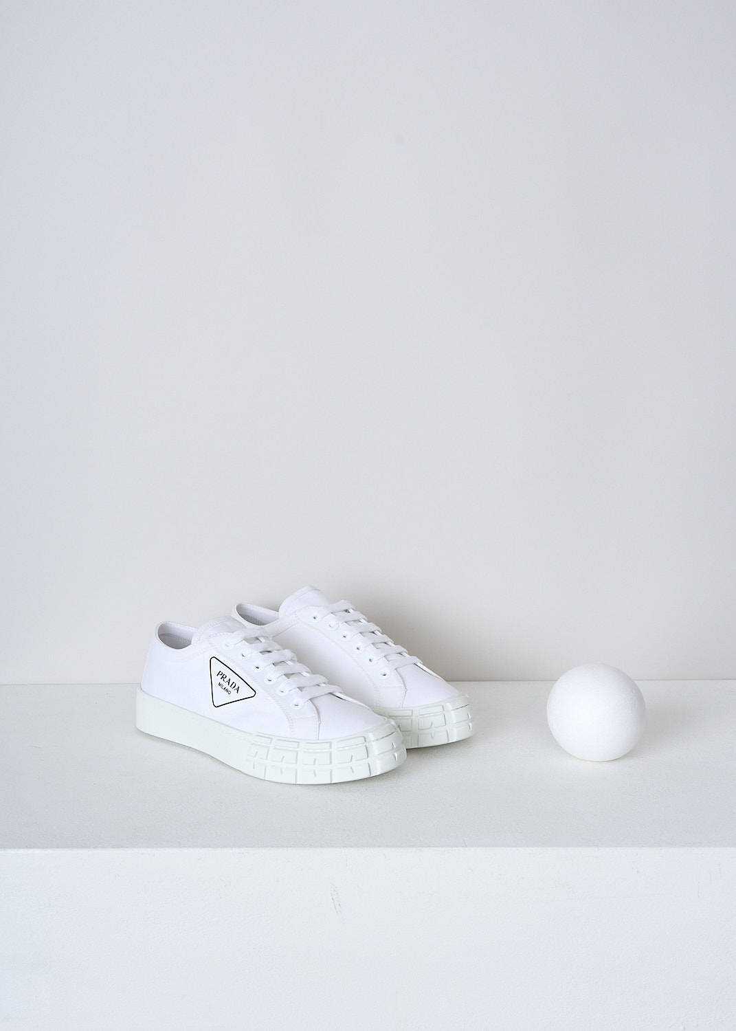 PRADA, ALL-WHITE CANVAS SNEAKERS, GUD_GABARDINE_1E939L_F0009_BIANCO, White, Front, These low top all-white canvas sneakers feature a front lace-up fastening with white laces. The brand's triangle logo can be found on the side in black. These sneakers have a round toe with a white rubber toe cap and ribbed rubber soles.
