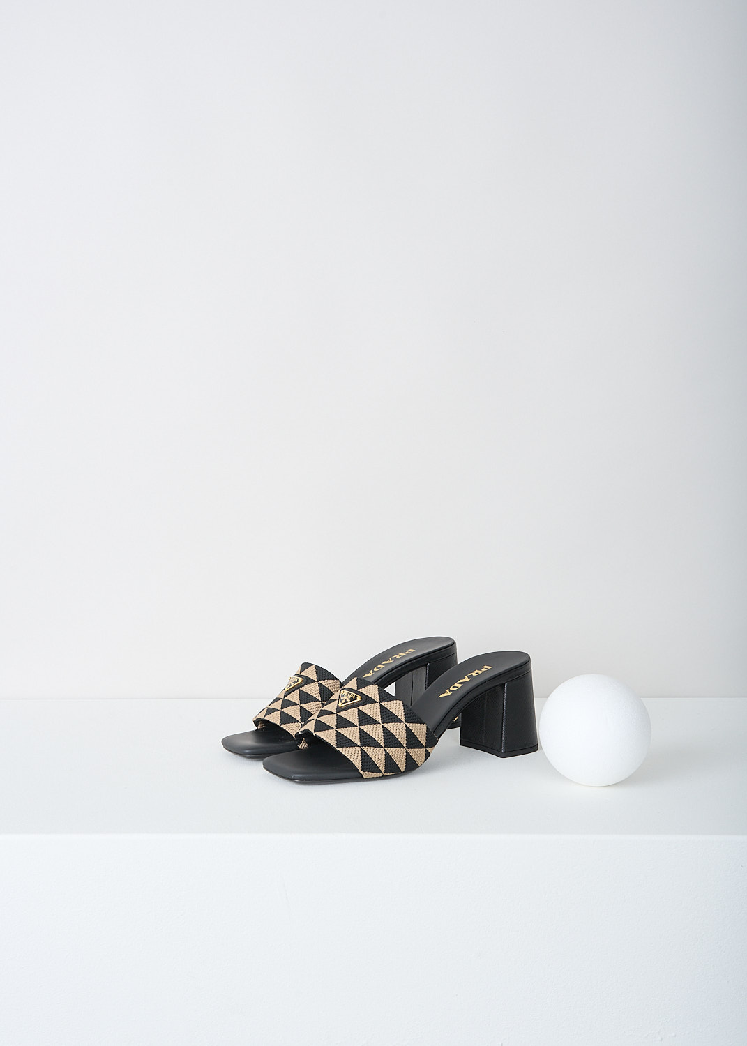 Prada, Black-and-beige triangolo mules, 3LK6_TRIANGOLO_JACQUARD_1XX637_F0Y30_NERO_CORDA_065, Black, Beige, Print, Front, These slip-on mules have a broad strap with a back-and-beige triangolo jacquard print. On the strap, the brand's triangle logo can be found in gold-tone metal. 
