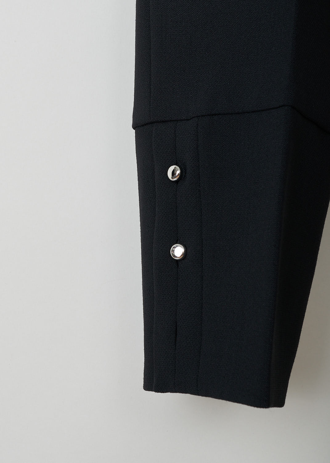 Prada, Black wool pants, Tela_Natte_STR_P2291_F0002_Nero, Black, Detail, These black wool pants have a waistband with belt loops and a concealed front zip closure. The pant legs have pressed creases and small buttoned slits 
