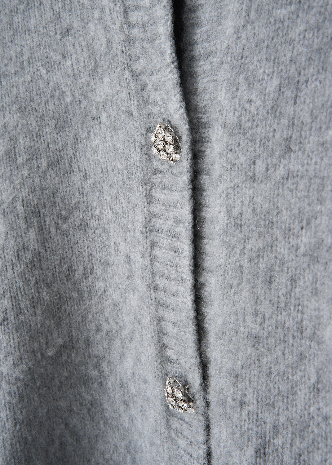 Close-up of crystal button front closure on light grey Prada cardigan at Kiki's Stocksale designer outlet boutique in Maastricht.