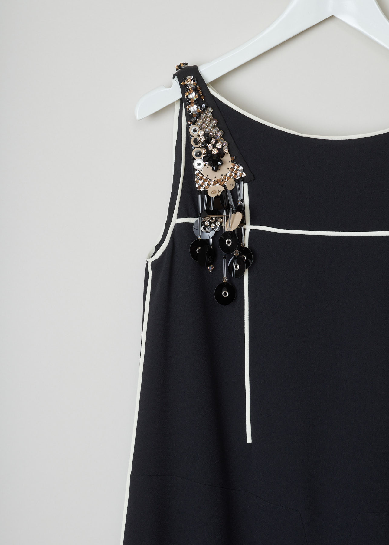 Prada, Black bead-and-sequin embellished dress, sable_piping_r_P33F7R_F0SJ2_nero_avorio_gris, Black, Detail, This black dress with white trimming has a bead and sequin embellished shoulder. There is a concealed zipper on the left side of the dress. The dress has a pleated flared skirt.
