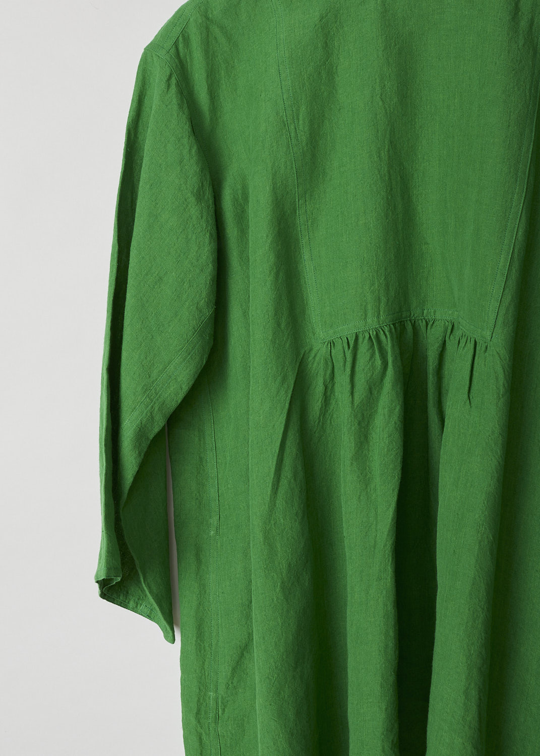 SOFIE D'HOORE, BRIGHT GREEN BINETTE TOP, BINETTE_LIFE_GRASS, Green, Detail, This oversized bright green top features a round neckline, dropped shoulders and long sleeves. The A-line top has a square bib-like front with pleated details below. Concealed in the side seams, slanted pockets can be found. The top has an asymmetrical finish, meaning the back is a little longer than the front. 


