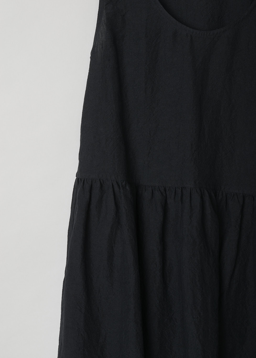 SOFIE Dâ€™HOORE, BLACK LINEN DANDLE DRESS, DANDLE_LIFE_BLACK, Black, Detail, This black sleeveless dress has U-neckline. The dress has a wide A-line silhouette. A straight crystal pleated hemline separates the bodice from the midi length skirt. Concealed slanted pockets can be found in the side seam. 
