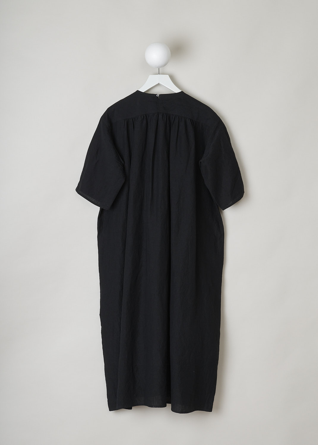 SOFIE Dâ€™HOORE, BLACK LINEN DARNELLE DRESS, DARNELLE_LIFE_BLACK, Black, Back, This oversized black midi dress features a round neckline, dropped shoulders and short sleeves. The A-line dress has a square bib-like front with pleated details below. Concealed in the side seams, slanted pockets can be found. The dress has a straight hemline with slits on either side. 


