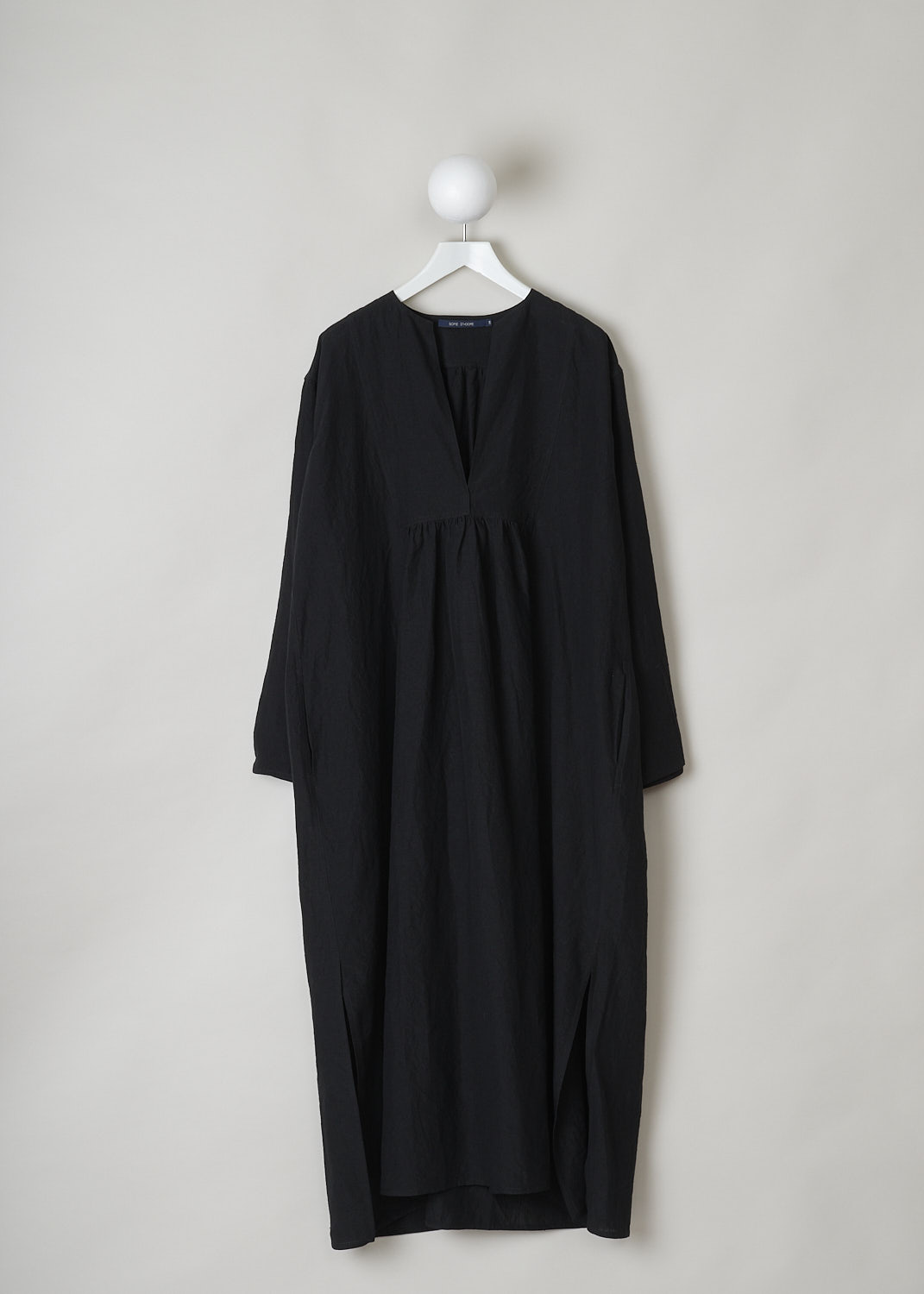 SOFIE Dâ€™HOORE, BLACK LINEN DELIZA DRESS, DELIZA_LIFE_BLACK, Black, Front,This black linen dress has a round neckline that goes into a deep V cutout. Subtle ruching can be found beneath the V. This long sleeve midi dress has a straight hemline with an asymmetrical finish, meaning the back is a little longer than the front. The dress has concealed slanted pockets and slits can be found on either side. The dress has a wide silhouette. 
