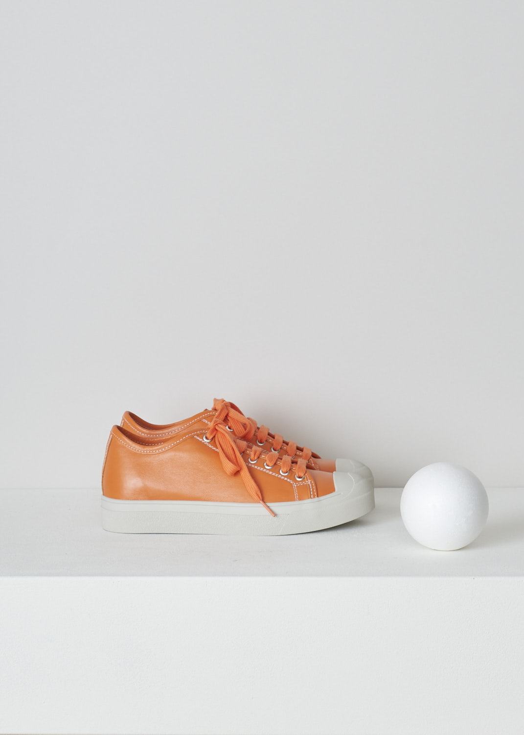 SOFIE Dâ€™HOORE, ORANGE LEATHER SHOES, FOLK_LMAST_LMAST_ORANGE, Orange, Side, These orange leather sneakers feature a front lace-up closure with orange laces. These sneakers have a round toe with a white rubber toe cap that goes down into the white rubber sole. Contrasting white stitching is used throughout. The sneakers come with an additional pair of white laces.
