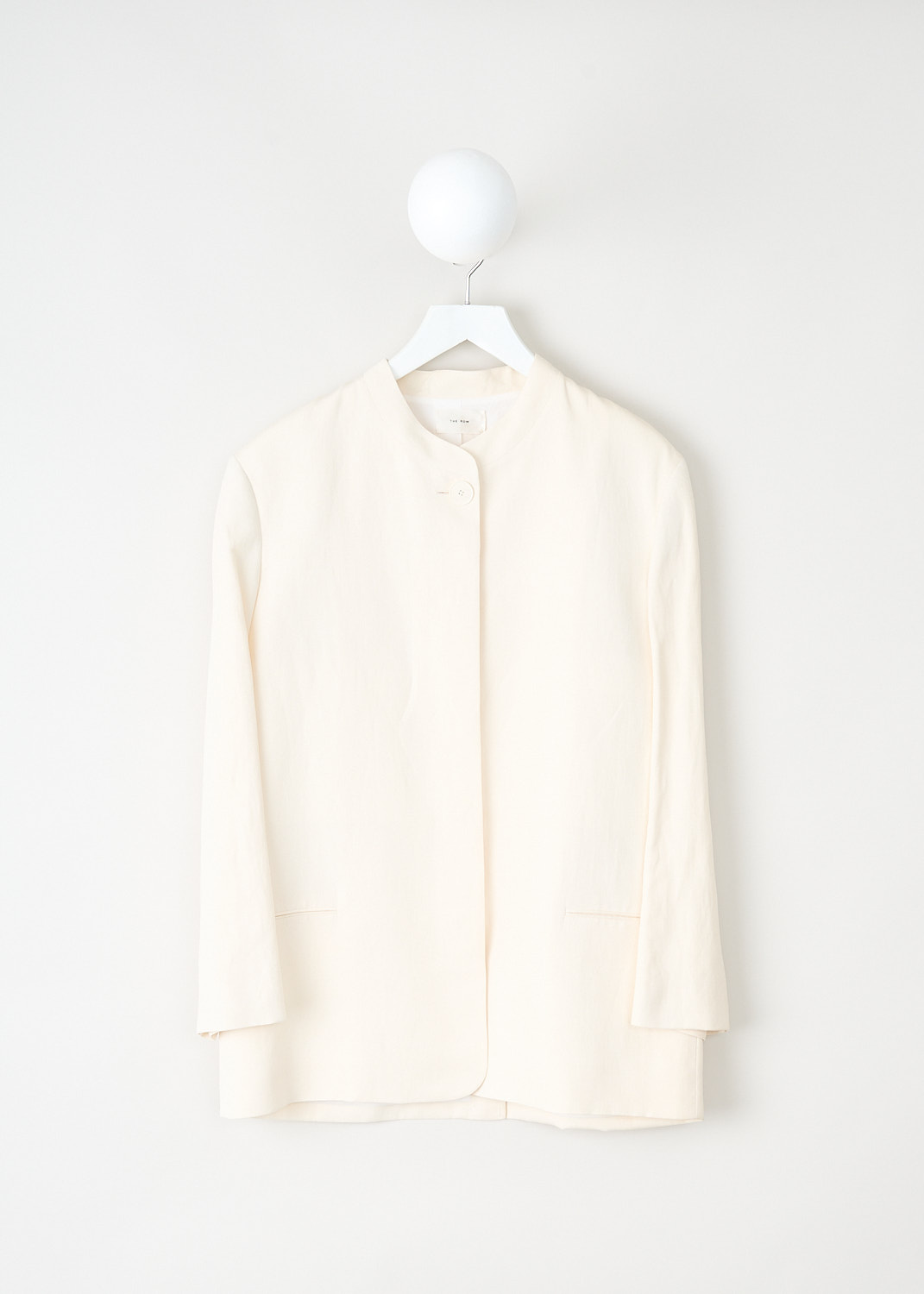 The Row, Aradia jacket in Ivory, ARADIA_JACKET_6011_W2166_IVORY, White, Front, This Aradia jacket in Ivory has a mandarin collar with a single exposed button and a concealed front button closure. The long sleeves have buttoned cuffs. On the front, the jacket has welt pockets. In the back, the jacket has a centre vent. 

