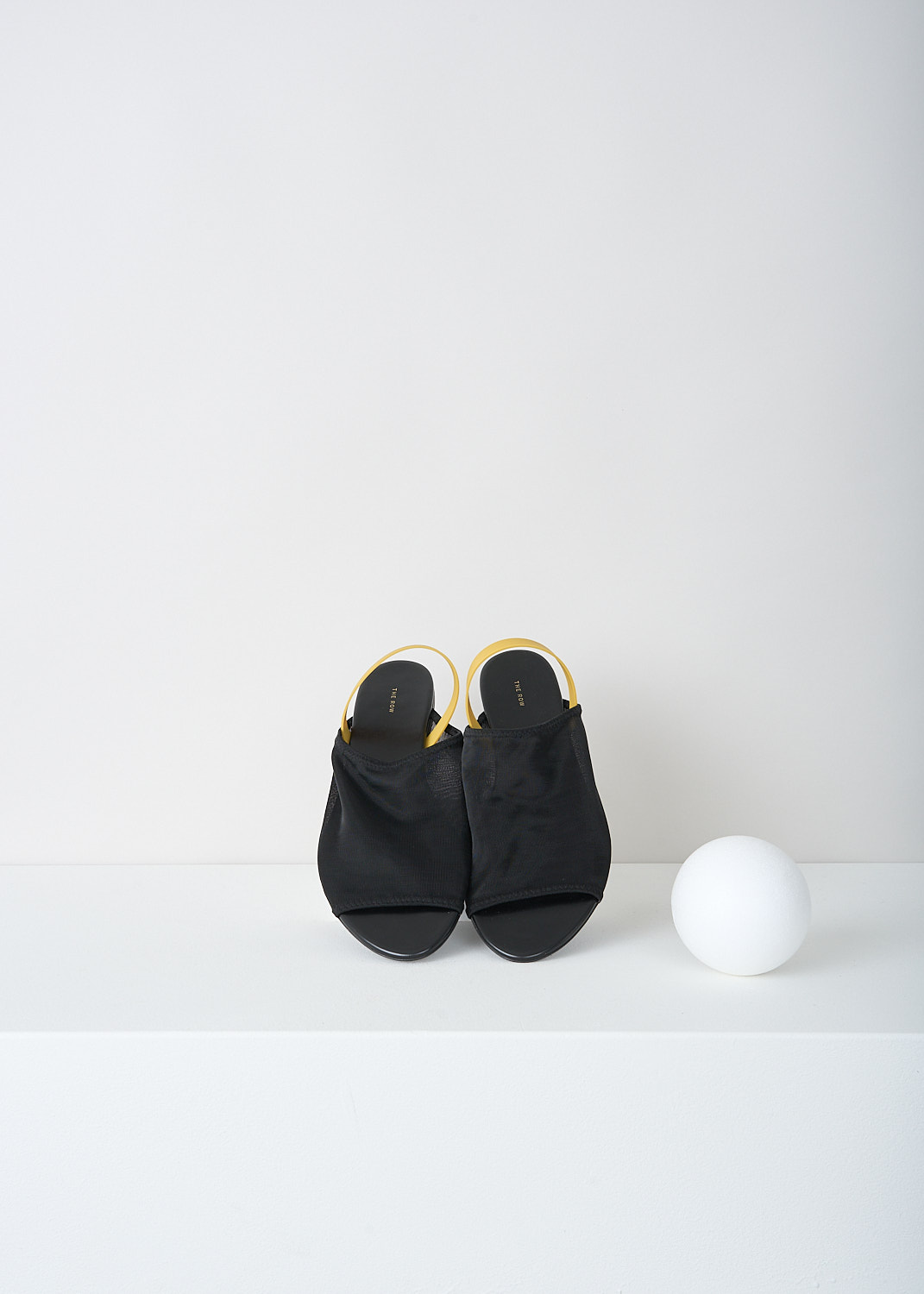 The Row, Black slingback sandal with yellow strap, CLEAR_SANDAL_F1164_W20_BLACK, Black, Yellow, Top, These black slingback sandals have a broad strap across the vamp and a round open toe. On the heel, these sandals have a slim contrasting yellow strap.
