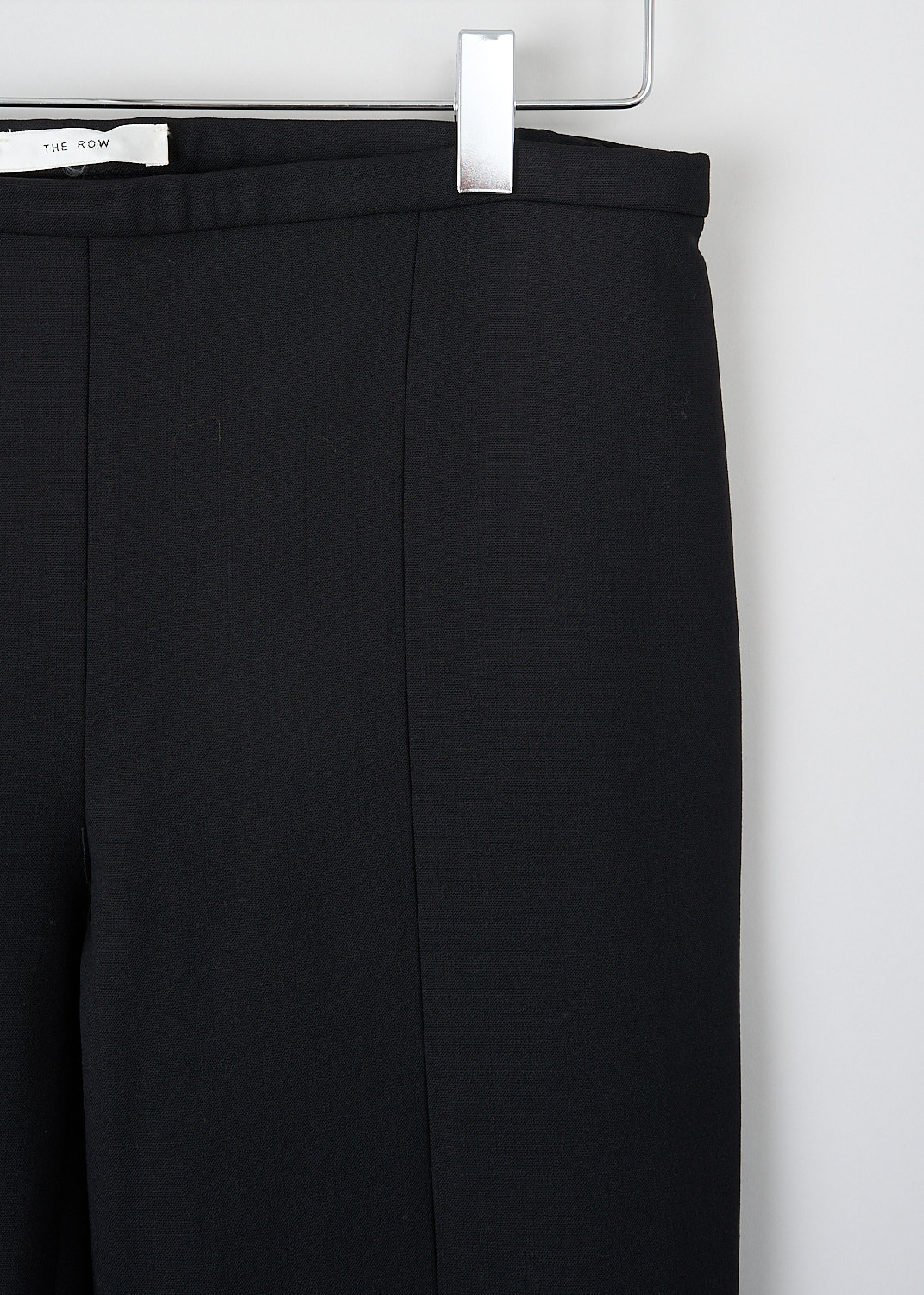 The Row, Sovino pants in black, SOVINO_PANT_5922W2119_BLACK, Black, Detail, These Sovino pants in black have a narrow waistband with a side zip closure. These pants have skinny pant legs with pressed creases. The hem has small side slits. 

