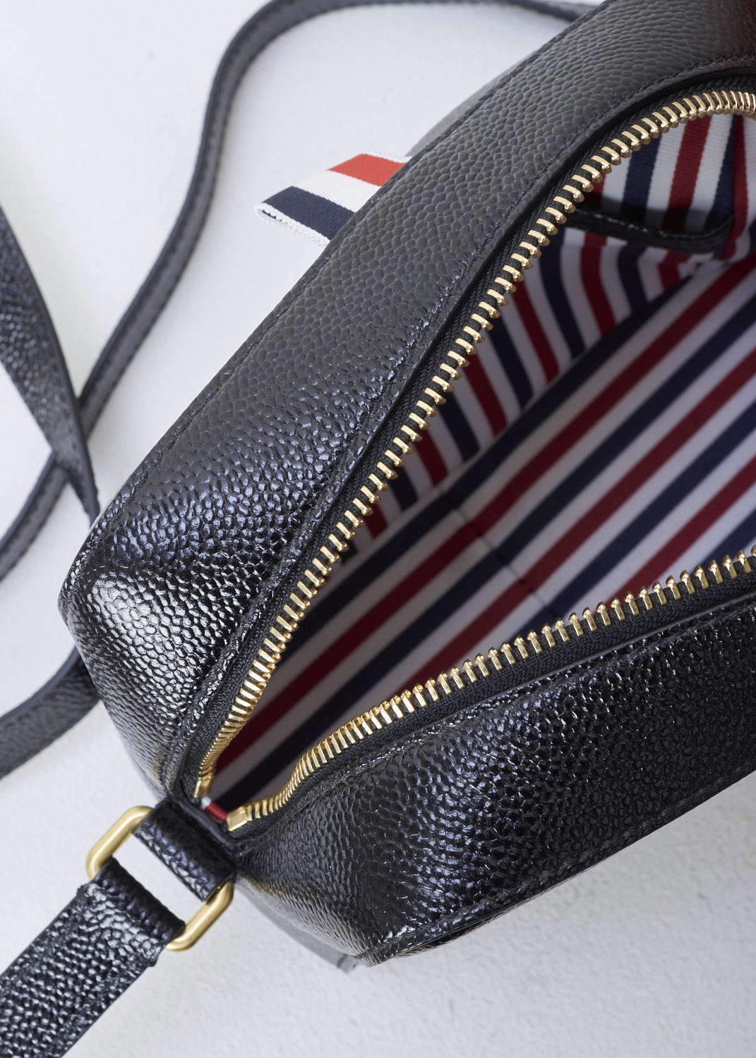 THOM BROWNE, CROSS BODY BAG WITH BOW DETAIL IN THE SIGNATURE TRI-COLOR STRIPE, FAP116A_03542_001, Black, Print, Detail 1, Leather cross body bag with a bow detail in the signature tri-color grosgrain stripe in the front and a single tri-colored tab on the back. This model is made with pebble grain leather. Up top, a gold-toned zipper gives access to the interior of the bag. The bag opens up to a single spacious compartment with on one side, a single patch pocket against the back wall. 


Size: 17 cm x 13 cm x 7 cm / 6.6 inch x 5.1 inch x 2.7 inch 

