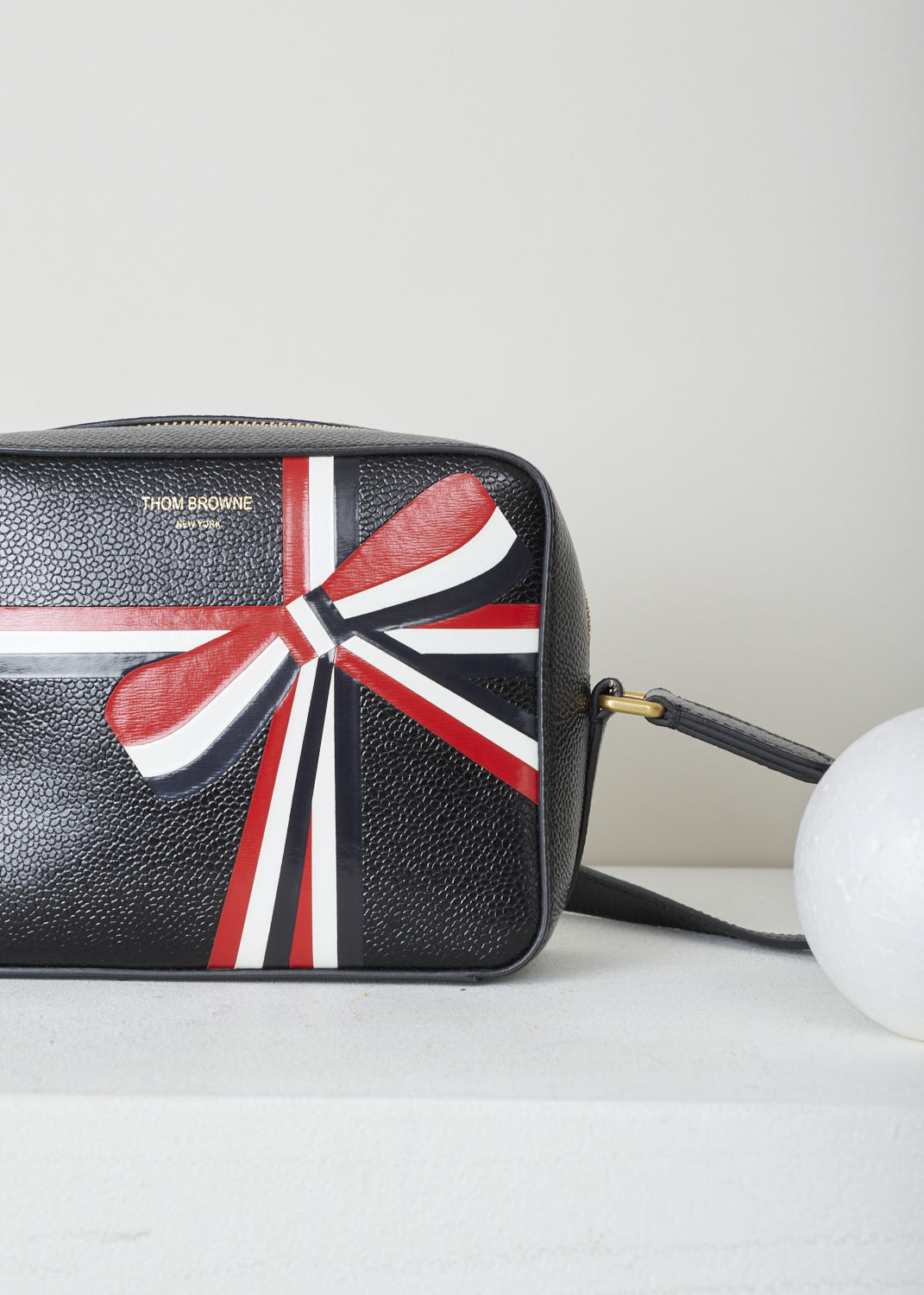 THOM BROWNE, CROSS BODY BAG WITH BOW DETAIL IN THE SIGNATURE TRI-COLOR STRIPE, FAP116A_03542_001, Black, Print, Detail, Leather cross body bag with a bow detail in the signature tri-color grosgrain stripe in the front and a single tri-colored tab on the back. This model is made with pebble grain leather. Up top, a gold-toned zipper gives access to the interior of the bag. The bag opens up to a single spacious compartment with on one side, a single patch pocket against the back wall. 


Size: 17 cm x 13 cm x 7 cm / 6.6 inch x 5.1 inch x 2.7 inch 
