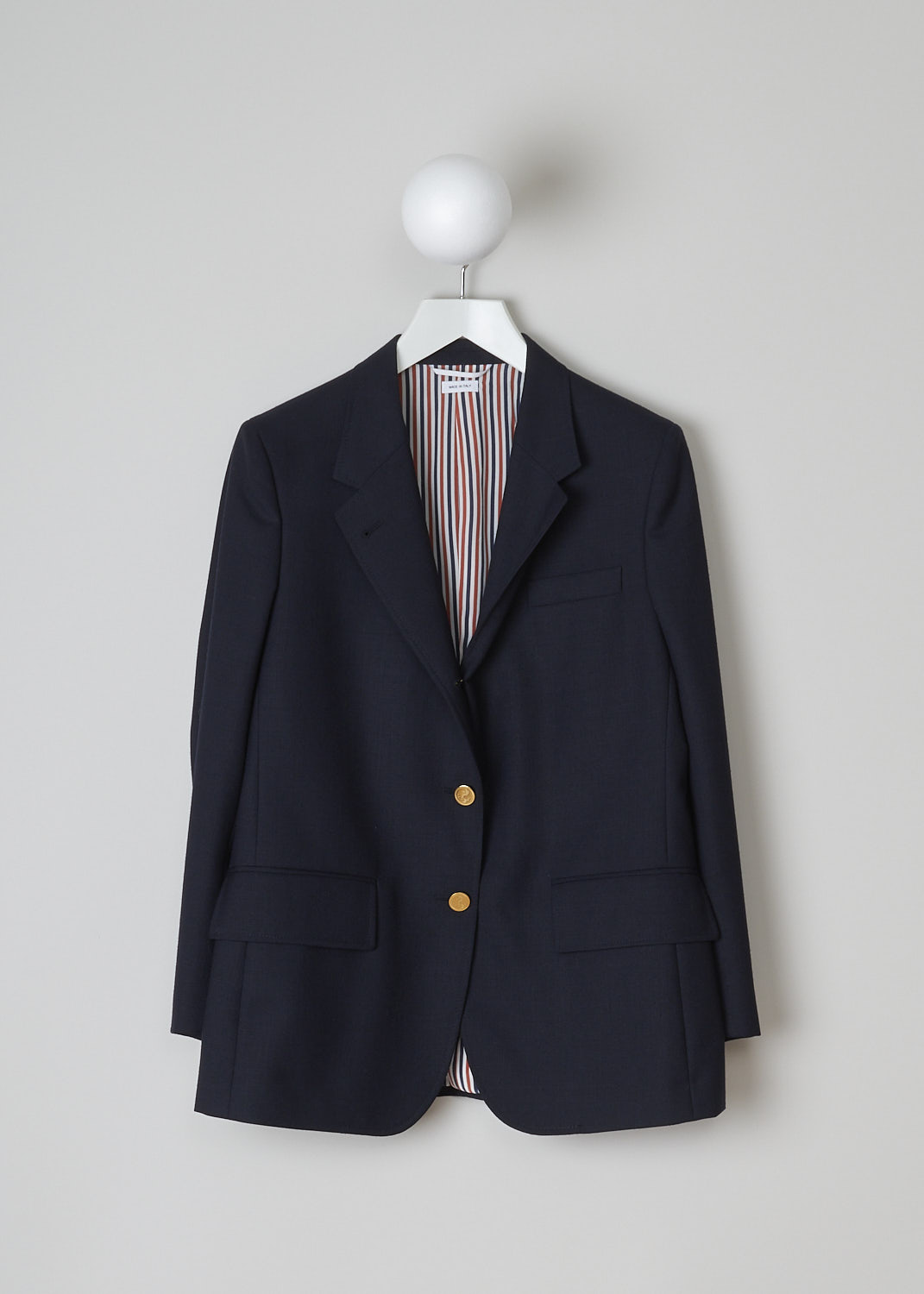 THOM BROWNE, DARK NAVY WIDE LAPEL SPORT JACKET, FBC357A_00473_415, Blue, Front, This dark navy sport jacket has a wide notched lapel and a front button closure with gold-tone buttons. The long sleeves have buttoned cuffs. In the front, the jacket has a single breast pocket and two flap welt pockets. O the inside, the jacket has a striped lining, three inner pockets and a name tag. The brand's signature grosgrain loop tab can be found in the back. The jacket has a double vent. 
