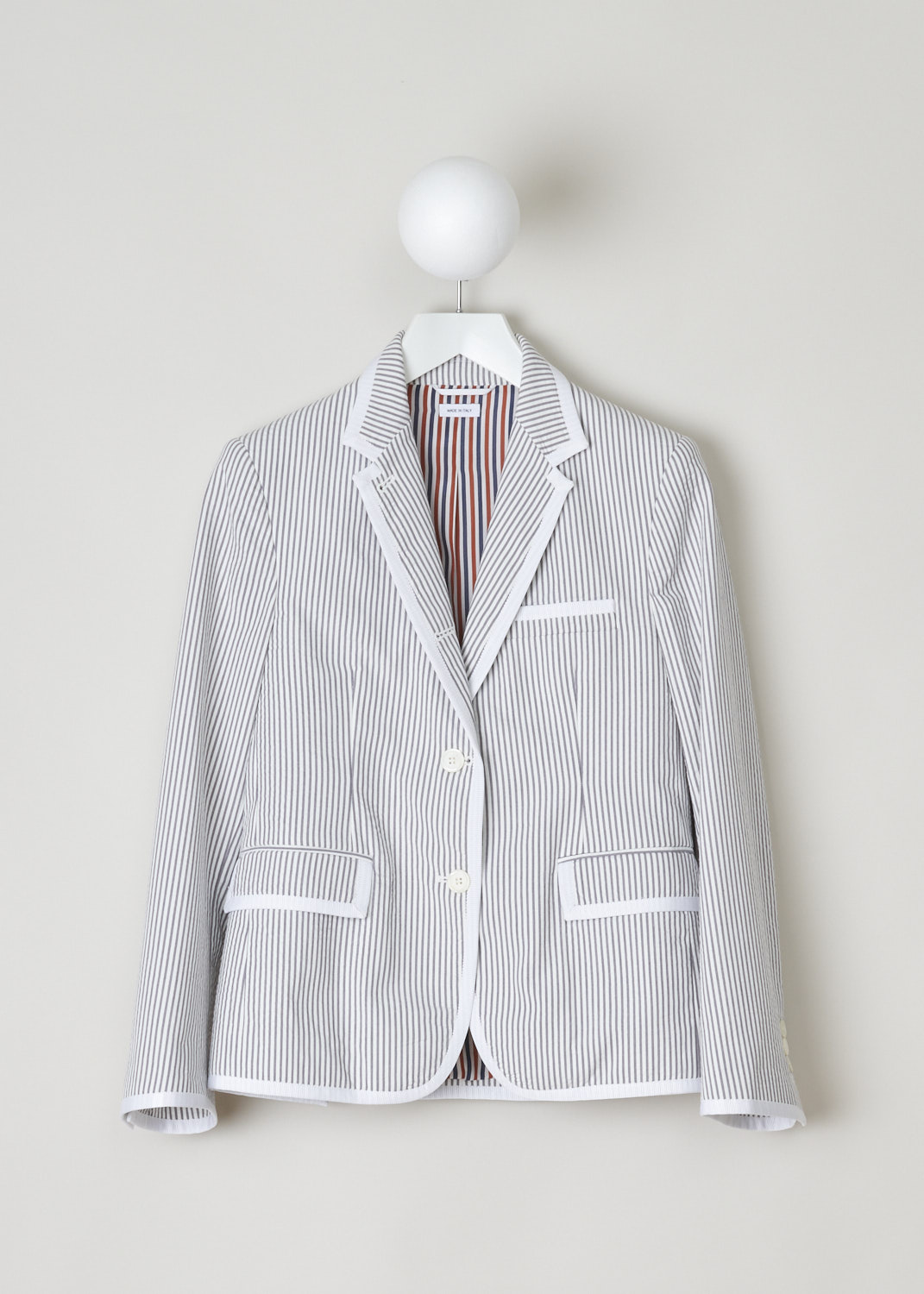 Thom Browne, white and grey striped blazer, FBC492B_00572_035, white grey, front, Classic blazer reimagined with the seersucker cotton fabric, and the lovely striped motif. Featuring a collar that leads into the notched lapel, further decorating the front are two flap pockets and a single chest pocket. A notable feature here is that all the edges and hems are adorned with a white trim. On the back you will find two off-center splits. 