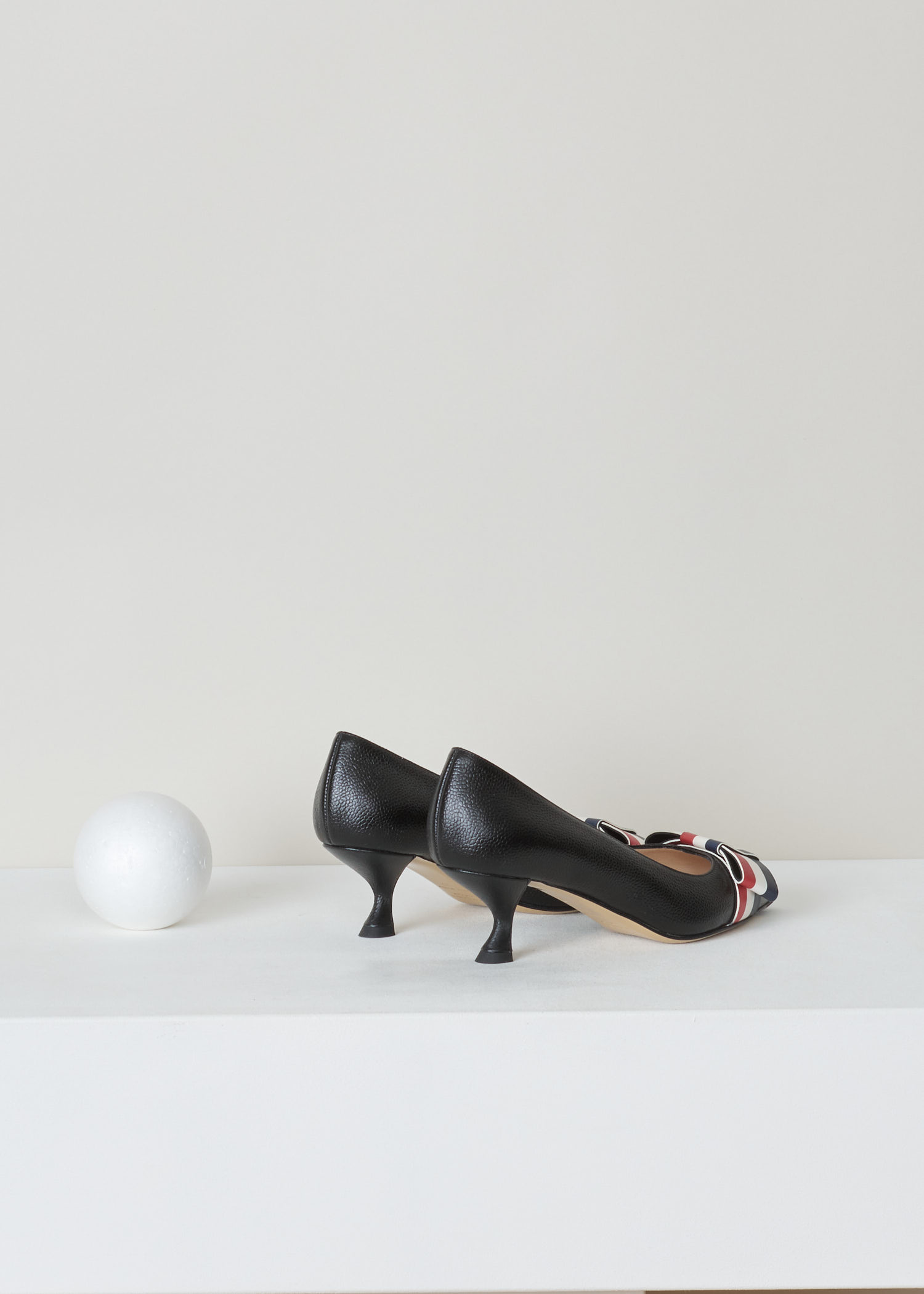 Thom Browne, Curved queenie heel pump, FFH121A_03542_001_black, black, back. High quality leather tooled until it got this beautiful pebble grain motive. As most of the Thom Browne items this gorgeous queenie heels pump also comes with the infamous rwb colours in the shape of a bow on the vamp of the shoe.   

heel height: 5 cm / 2 inch. 