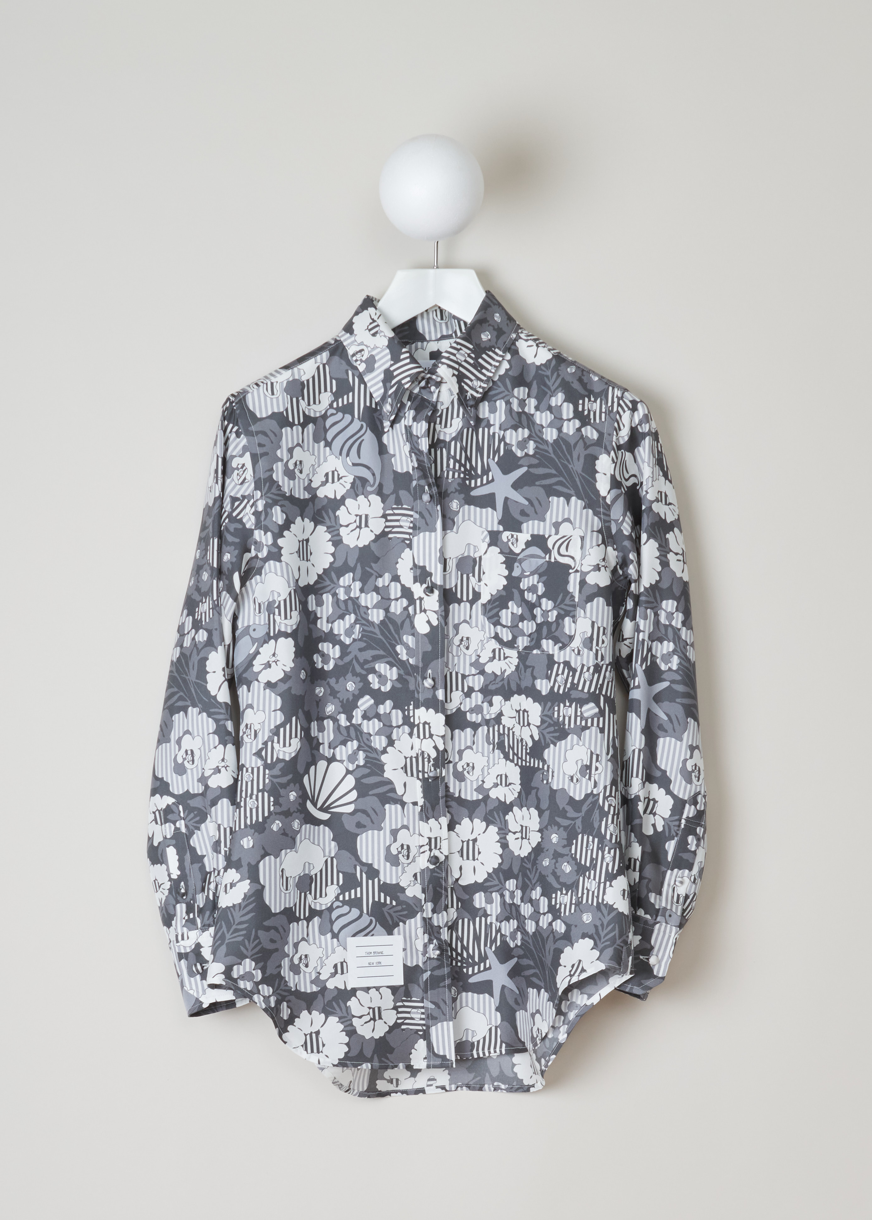 Thom Browne Sunny floral print shirt FLL005A_06160_035_Med_Grey front. Long sleeved shirt in the sunny floral pattern with a pointed, buttoned collar, a chest pocket, an exterior name tag, buttoned cuffs and a rounded hem.