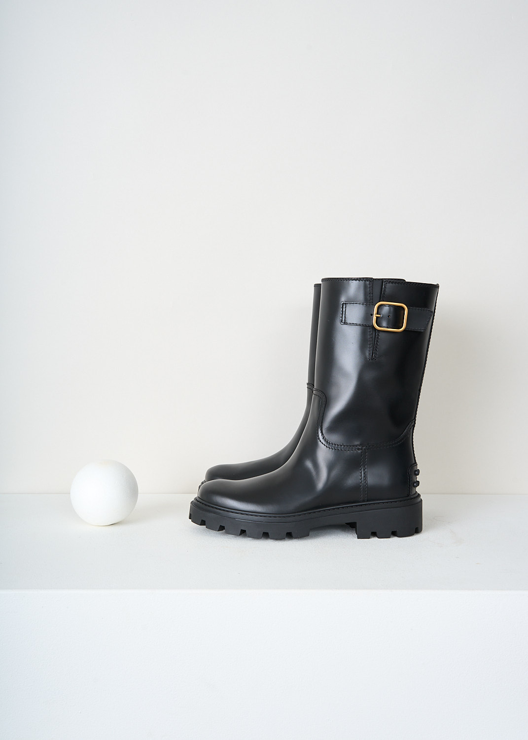 Tod’s black leather slip-on boots with a decorative buckle on the outer side, classic round toe and signature studded heel detail – high-end designer footwear at Kiki’s Stocksale Maastricht.