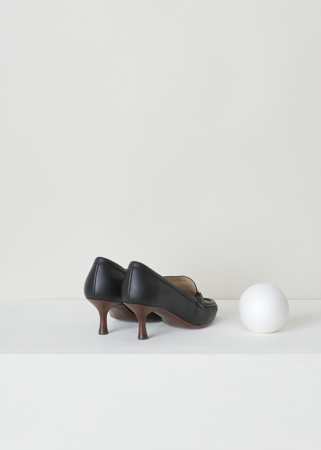 TODS, BLACK LEATHER LOAFERS WITH A TRAPEZOID HEEL, XXW09D0EC80_MID_B999_NERO, Black, Back, Black leather loafers with a wooden spool heel. This model has a pointed toe and a gold-tone buckle decorating the front. Around the trim, the leather is subtly pleated.
