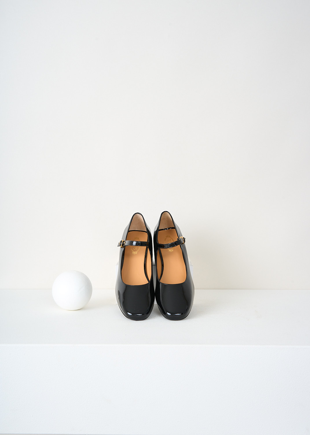Top view of Tod’s black patent leather pumps highlighting the classic Mary Jane strap and signature gold-tone hardware – designer fashion footwear from Kiki’s Stocksale designer boutique Maastricht.