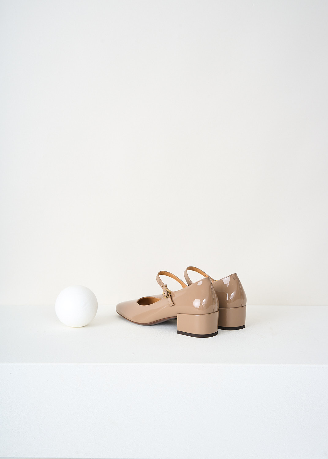 Rear view of beige Tod’s Mary Jane pumps showcasing the small block heel, ankle strap and sleek patent leather finish – premium designer shoes available at Kiki’s Stocksale Maastricht.