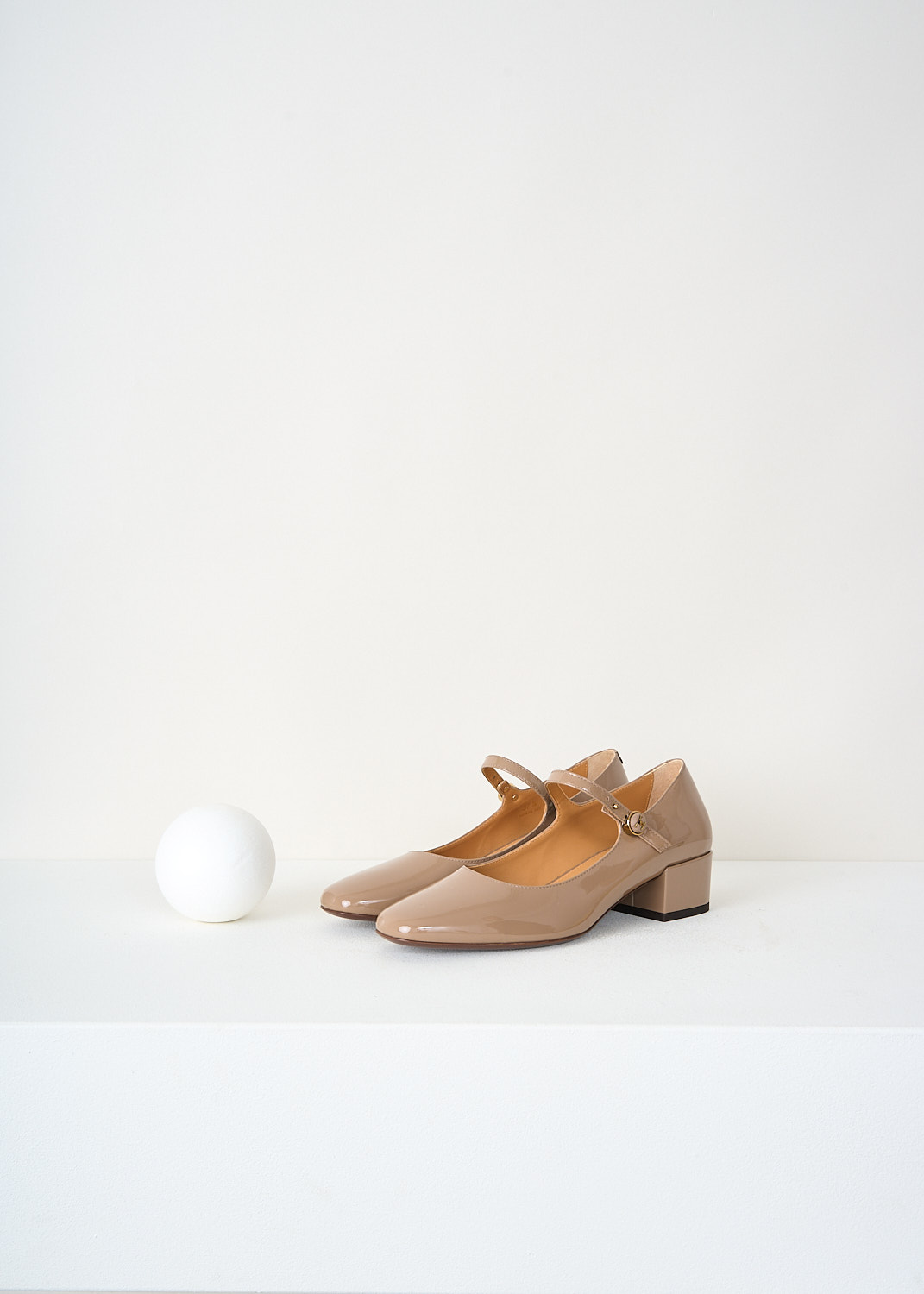 Front view of beige Tod’s Mary Jane pumps featuring a polished patent finish, round toe and signature gold-tone buckle – designer sale footwear from Kiki’s Stocksale.