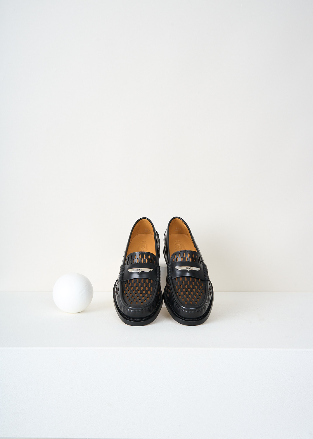 Top view of Tod’s black leather loafers highlighting the all-over laser-cut pattern and decorative slotted leather strip – luxury footwear from Kiki’s Stocksale designer boutique Maastricht.