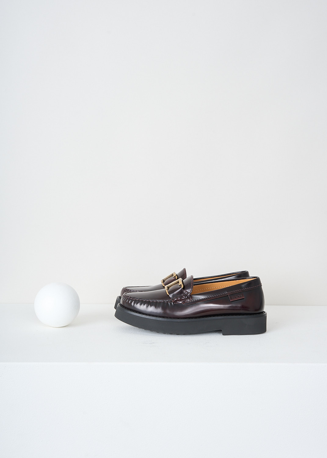 Tod's, Dark brown moccasins with gold-tone buckle, XXW54K0HN90_SHA_R810, Brown, Side, These dark brown leather moccasins have a almond toe and a gold-tone 'T' logo over the topside. These shoes have black rubber soles. 
