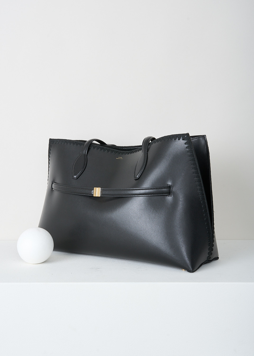 Toteme, Black leather lounge tote bag, 253_WAL0073_LE0025_001_BLACK, Black, Side, This black leather Lounge tote bag has two fixed shoulder straps and a lobster-clasp closure. Gold-tone hardware has been used throughout. On the front, the brandd's logo can be found in gold-tone lettering. The bag has a spacious main compartment with an inner slip pocket.
