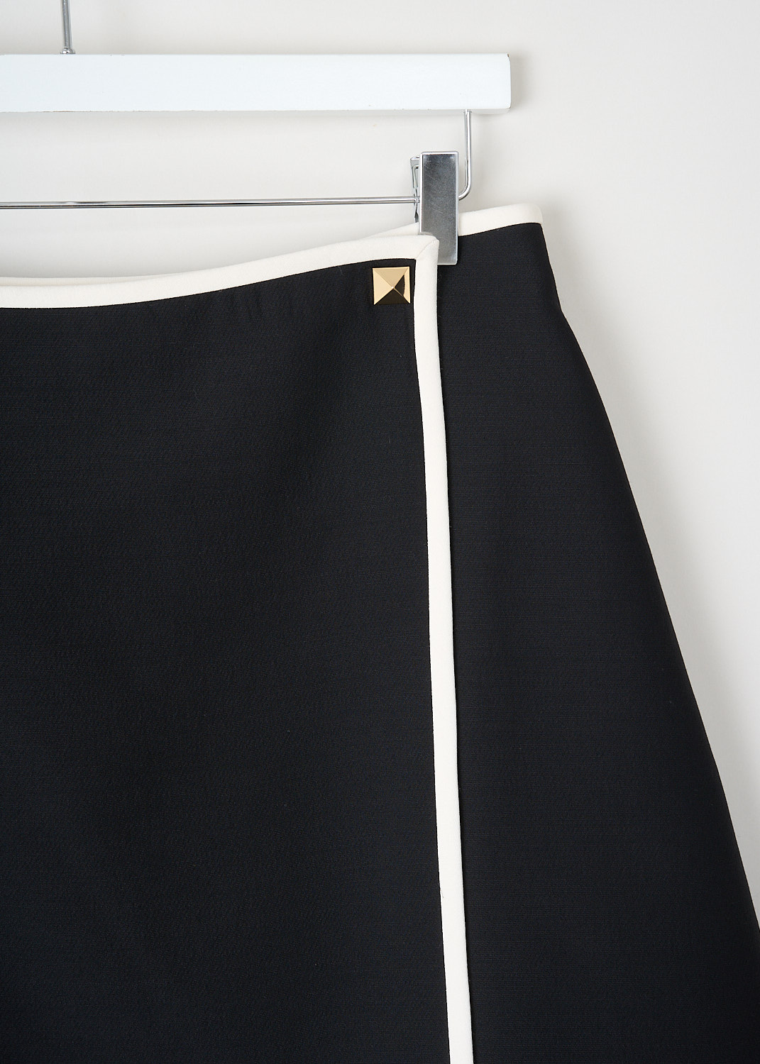 This skirt has a gold-tone square stud waist closure with light contrast trim on a structured black design, available at Kiki’s Stocksale Maastricht designer outlet.