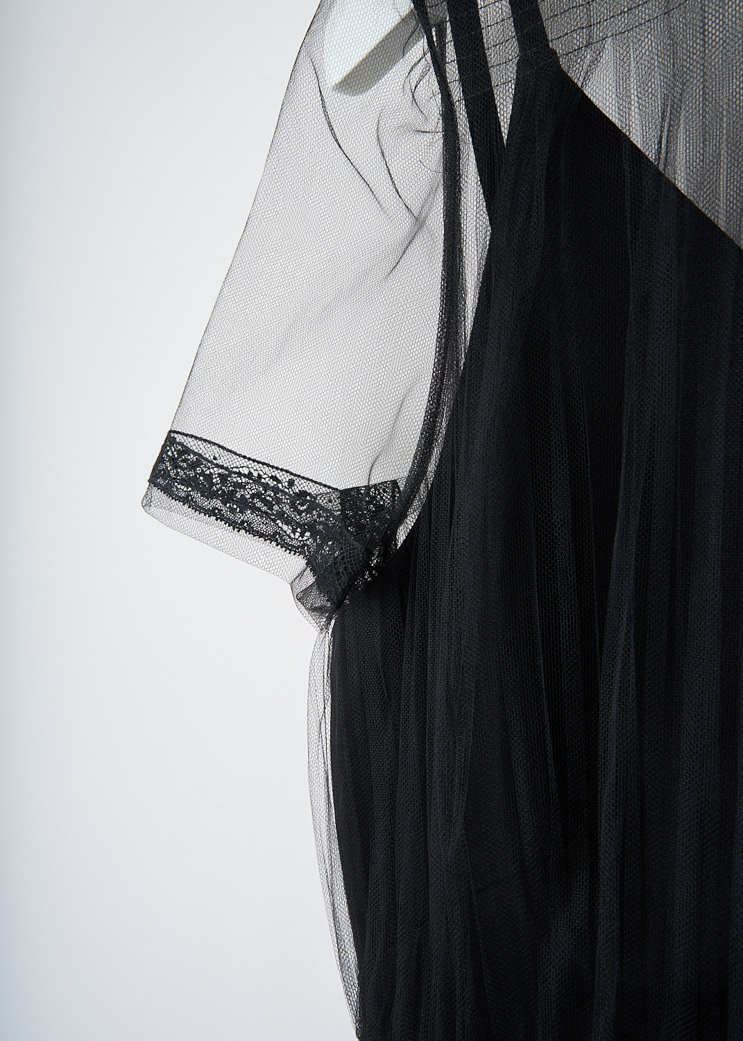 Close-up detail of Valentino black midi dress showing sheer mesh overlay, lace trim at neckline and sleeve cuffs, and layered construction