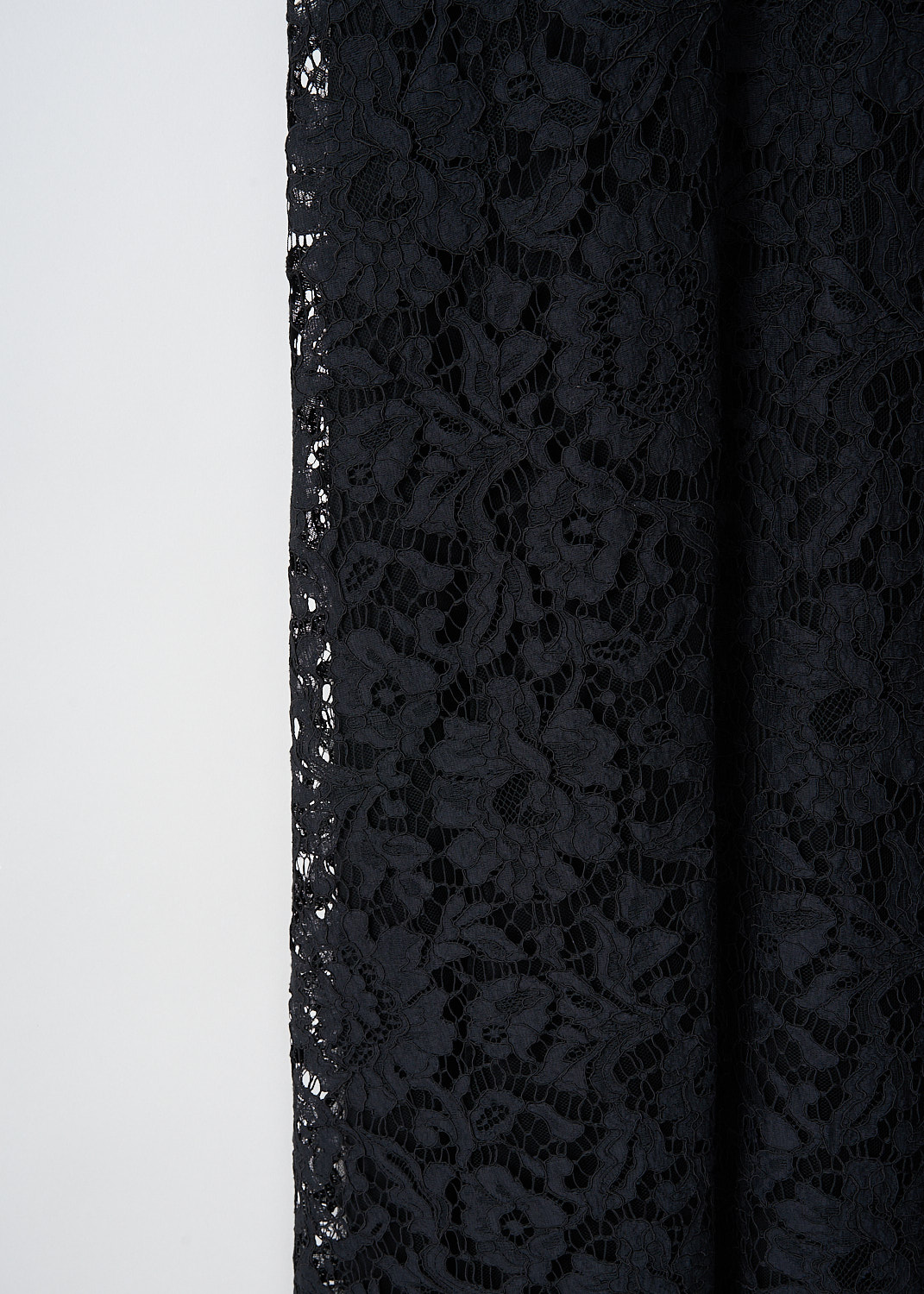 Close-up detail of black lace fabric and delicate straps on maxi dress